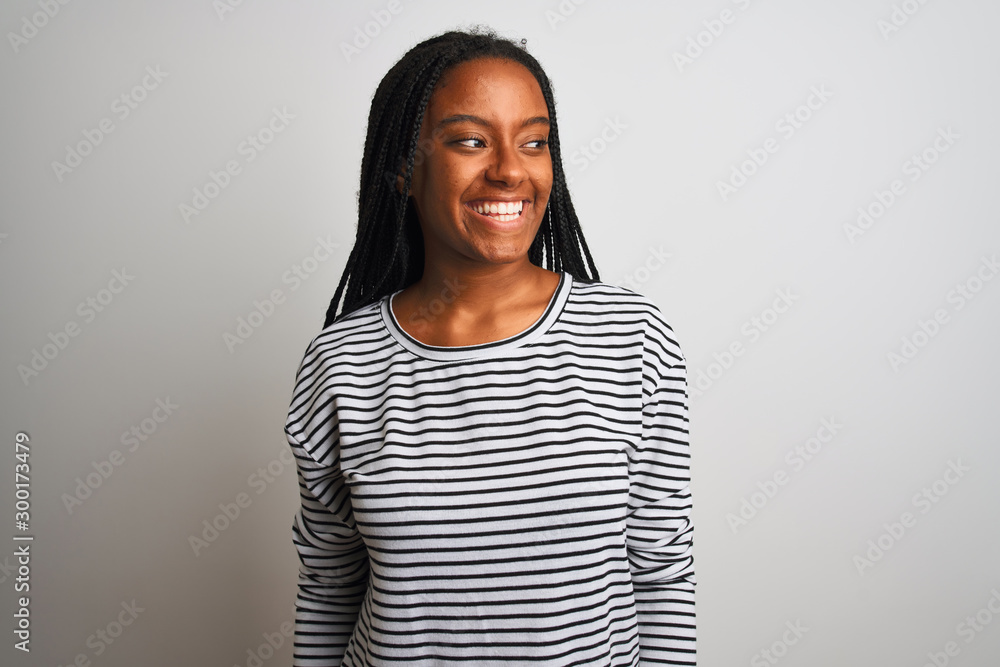Young african american woman wearing striped t-shirt standing over isolated white background looking away to side with smile on face, natural expression. Laughing confident. Young african american woman wearing striped t-shirt standing over isolated white background looking away to side with smile on face, natural expression. Laughing confident.