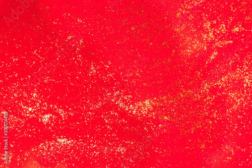 Golden glitter on red paper background. Christmas or Valentine's background. Flat lay