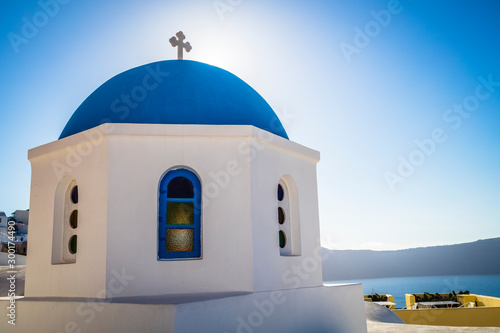 Traditional white architecture and greek orthodox churches with blue domes over the Caldera in Aegean