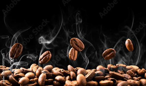 Fotografering Coffee beans fall in smoke on a black background. Roasting coffee