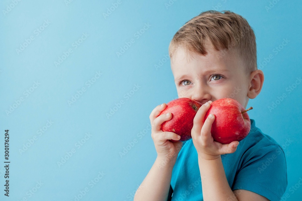 Little Boy Holding an Apples in his hands on blue background, diet and exercise for good health concept Little Boy Holding an Apples in his hands on blue background, diet and exercise for good health concept