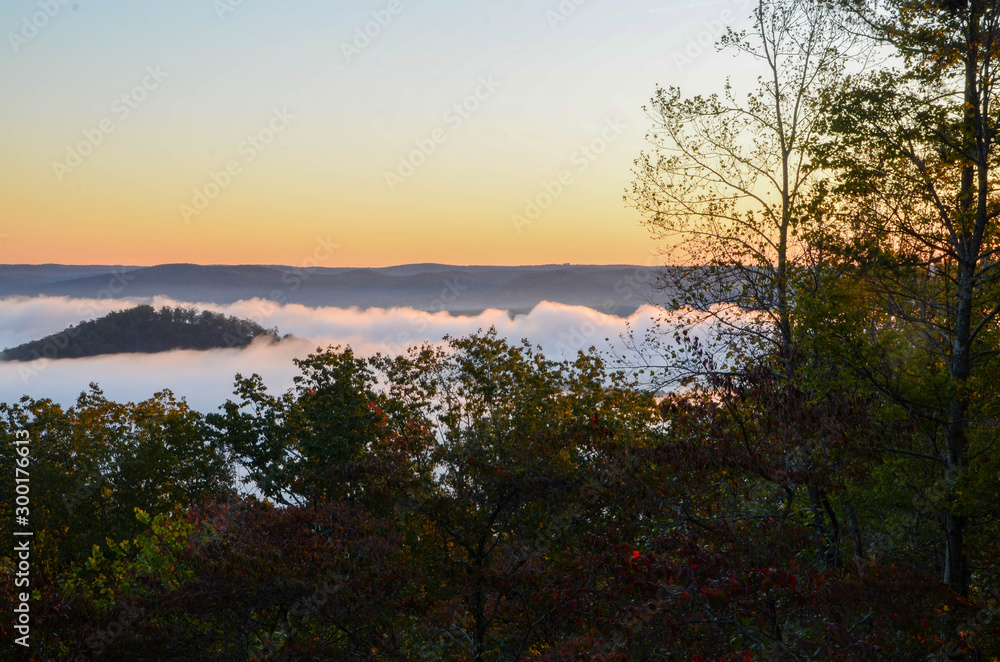 Early morning fog blankets the valley below. On a sunrise fall morning.