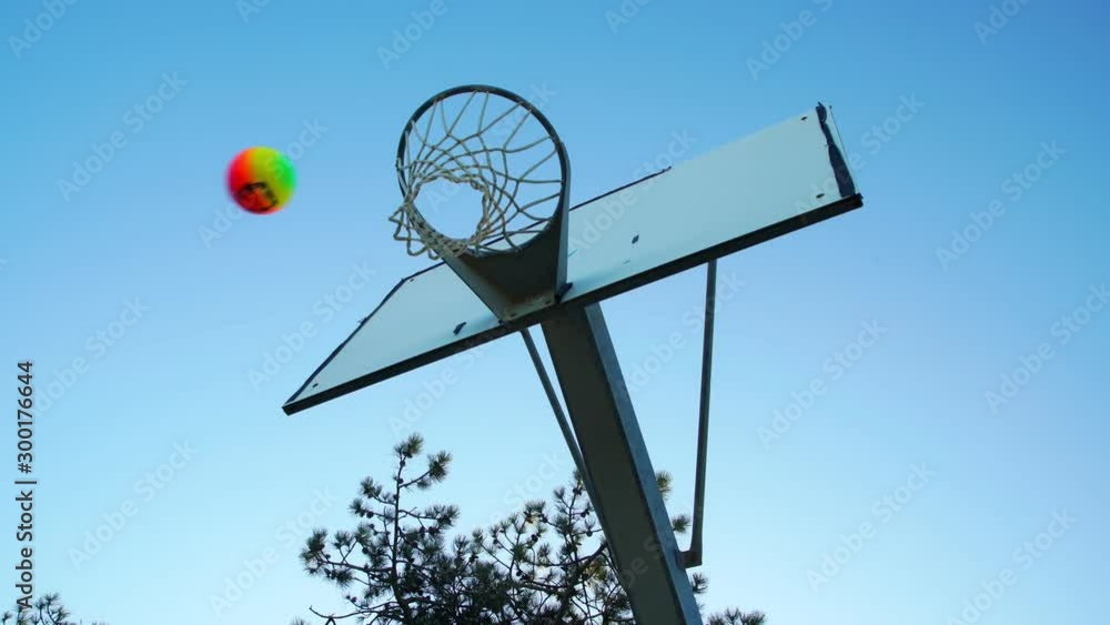 yellow pink and violet ball beats and misses basket in green outdoor space against clear evening sky low angle shot yellow pink and violet ball beats and misses basket in green outdoor space against clear evening sky low angle shot