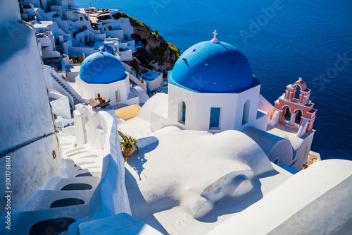 Traditional white architecture and greek orthodox churches with blue domes over the Caldera in Aegean © hardyuno