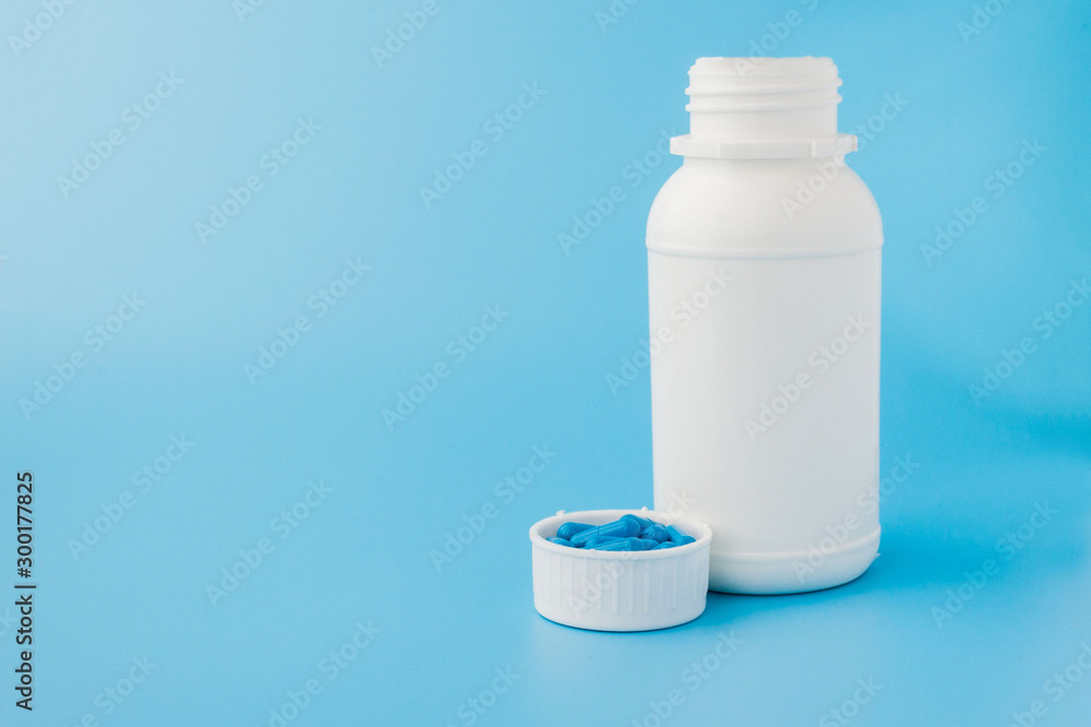 Blue capsules, pills on a blue background. Capsules in a white jar. Vitamins, nutritional supplements for women's health Blue capsules, pills on a blue background. Capsules in a white jar. Vitamins, nutritional supplements for women's health