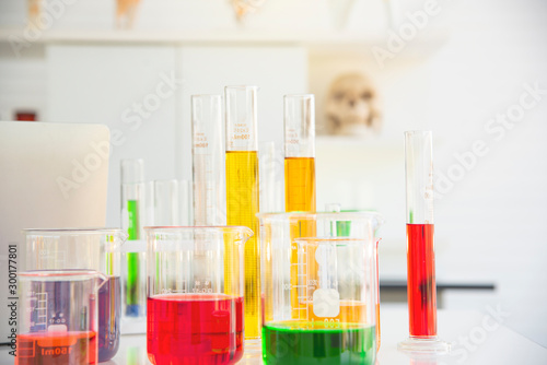 Several test tubes and solution beakers in a science laboratory with liquid of different colors on the laboratory table for chemical background