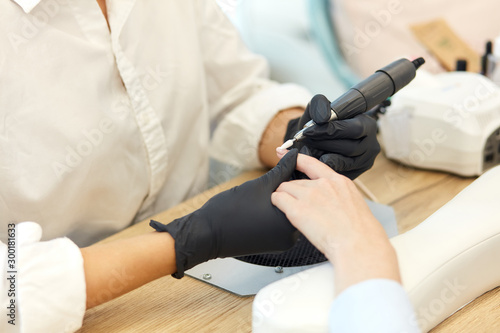 Manicurist in black gloves do mechanical manicure of nails. Closeup of beautiful hands. clean and sterile