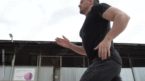 An athletic man walks with his back to the camera.
