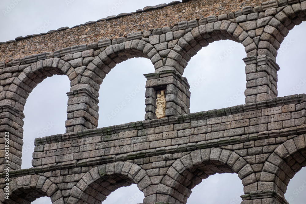 Segovia aqueduct on a cloudy, detail of the sculpture of the Virgin of Fuencisla