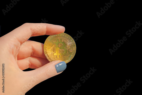 Woman hand holding gold bitcoin/cyptocurrency isolated on black background, close up.  Finance concept photo