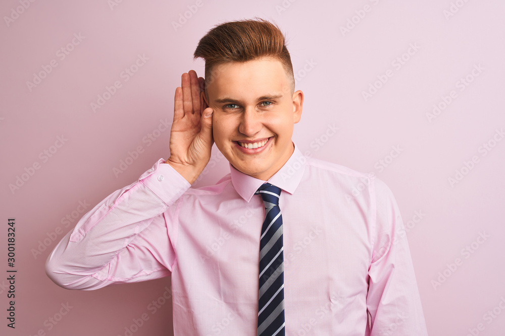 Young handsome businessman wearing shirt and tie standing over isolated pink background smiling with hand over ear listening an hearing to rumor or gossip. Deafness concept. Young handsome businessman wearing shirt and tie standing over isolated pink background smiling with hand over ear listening an hearing to rumor or gossip. Deafness concept.