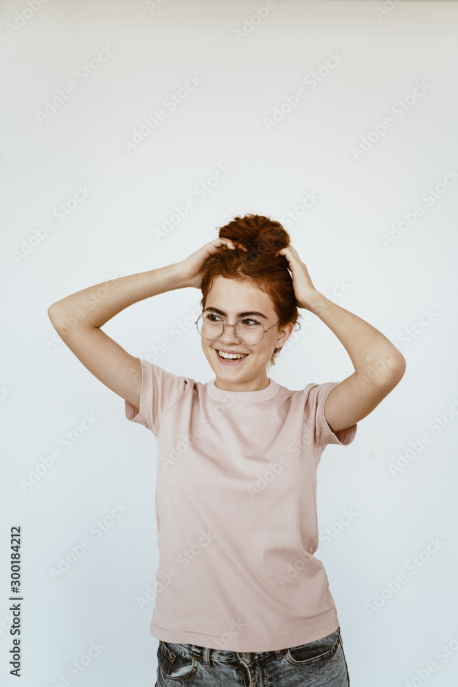 a schoolgirl with glasses laughs and straightens her hair with her hands. bright studio a schoolgirl with glasses laughs and straightens her hair with her hands. bright studio