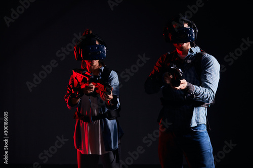 Youg couple direct their virtual weapons at camera, in search of enemy, virtual war. Futuristic, fantasy, innovation concept