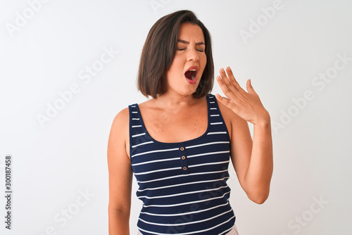 Young beautiful woman wearing blue striped t-shirt standing over isolated white background bored yawning tired covering mouth with hand. Restless and sleepiness.