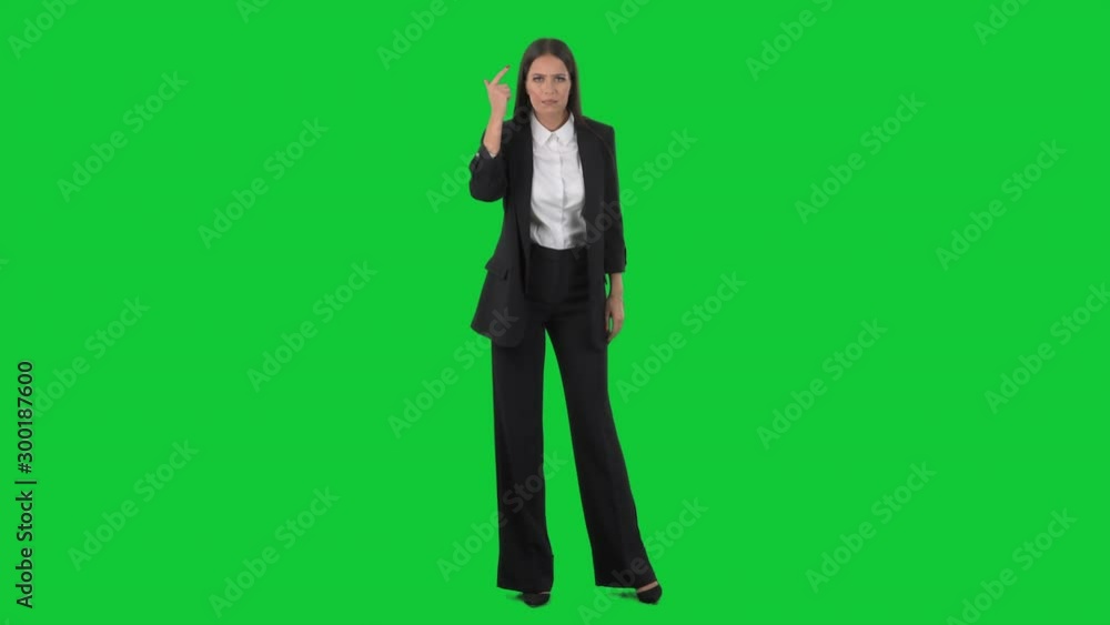 Upset young business woman looking at camera showing crazy spinning finger on temple gesture. Full length on green screen background. Upset young business woman looking at camera showing crazy spinning finger on temple gesture. Full length on green screen background.