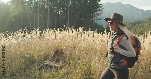 Woman hiking backpacker traveler camper walking on the top of mountain in sunny day under sun light. Beautiful mountain landscape view. 4K slow motion video