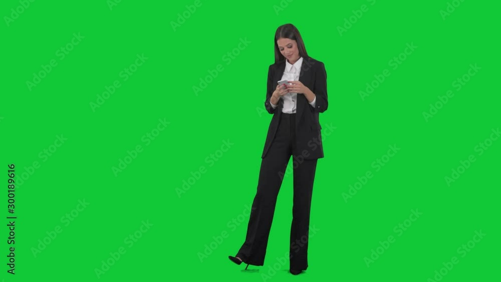 Relaxed happy young business woman typing messages on smart phone. Full length on green screen background. Relaxed happy young business woman typing messages on smart phone. Full length on green screen background.