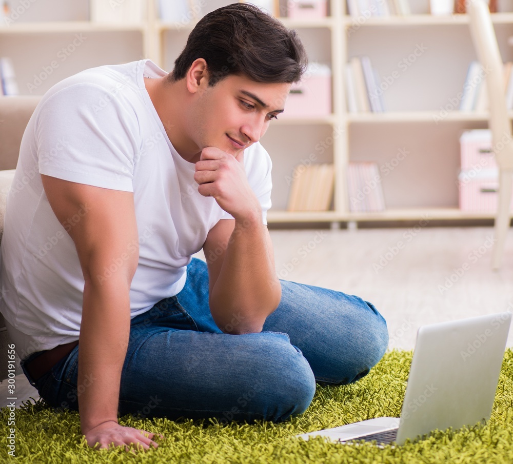 The man working on laptop at home on carpet floor The man working on laptop at home on carpet floor