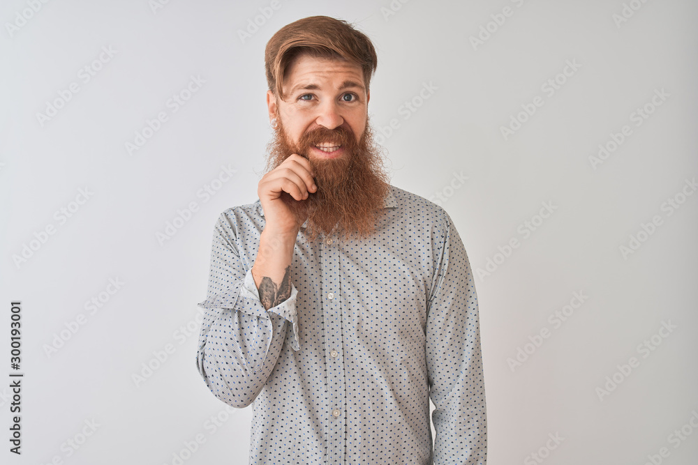 Young redhead irish man wearing casual shirt standing over isolated white background with hand on chin thinking about question, pensive expression. Smiling with thoughtful face. Doubt concept. Young redhead irish man wearing casual shirt standing over isolated white background with hand on chin thinking about question, pensive expression. Smiling with thoughtful face. Doubt concept.