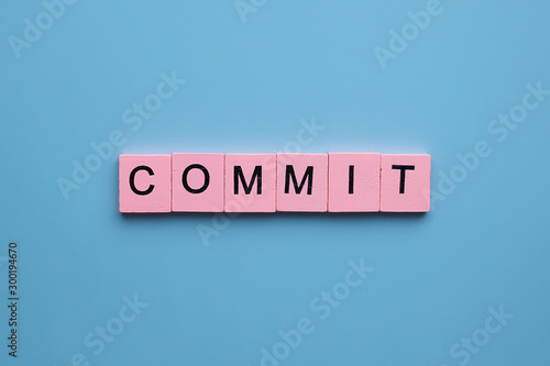 Commit word wooden cubes on blue background