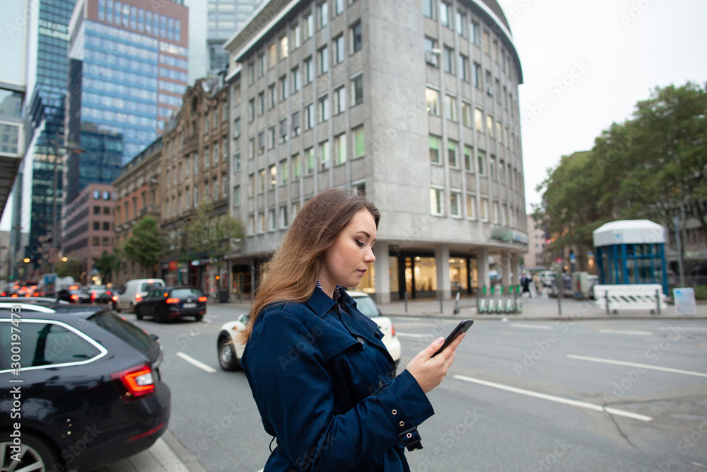 Business woman looking a location in the phone, for a business meeting. Half length photo. Germany, Frankfurt Business woman looking a location in the phone, for a business meeting. Half length photo. Germany, Frankfurt