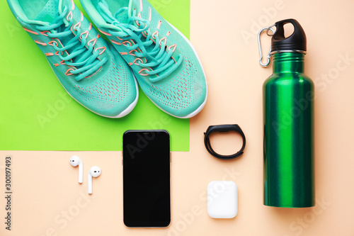 Sports water bottle, shoes, mobile phone and gadgets on color background