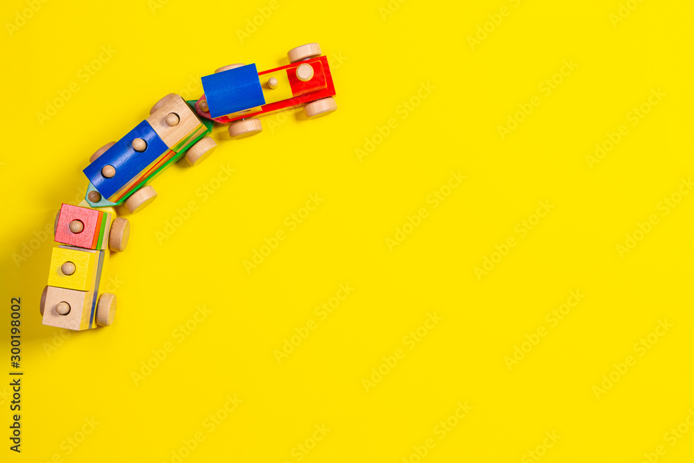 Fototapeta premium Wooden toy train with colorful blocks on yellow background