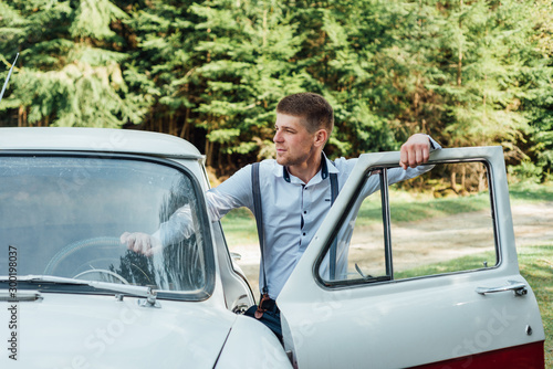 Portrait elegant fiance in a white shirt. Man standing near old car © dvv1989