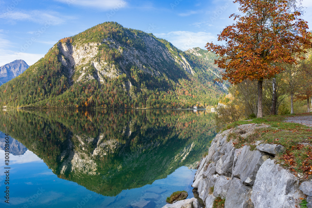 Mountains are reflected in the water of a mountain lake. The picture is taken in Alps at Plansee in Austria
