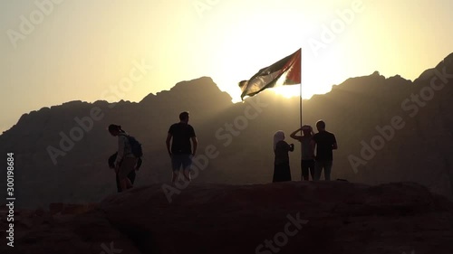 Tourists watching sunset while standing under Jordanian flag, Petra, Jordan
