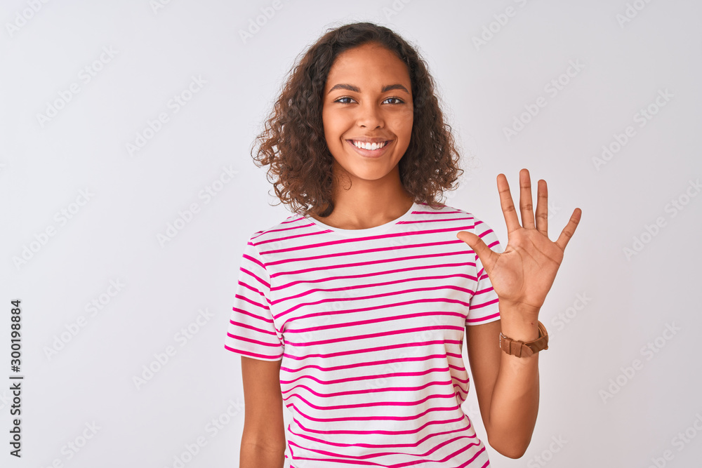 Young brazilian woman wearing pink striped t-shirt standing over isolated white background showing and pointing up with fingers number five while smiling confident and happy. Young brazilian woman wearing pink striped t-shirt standing over isolated white background showing and pointing up with fingers number five while smiling confident and happy.
