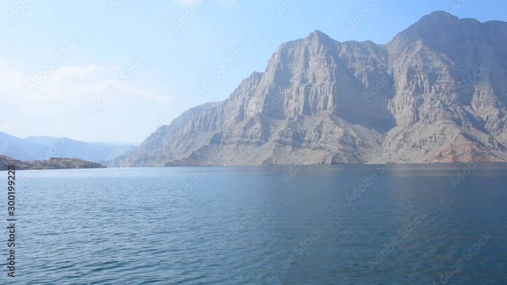 Blue waters of Musandam, Oman on a Dhow Boat trip in the Middle East the fjords, rocky mountains, and blue water near Strait of Hormuz Blue waters of Musandam, Oman on a Dhow Boat trip in the Middle East the fjords, rocky mountains, and blue water near Strait of Hormuz