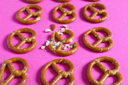 Photo Crushed pretzel among whole ones on color background
