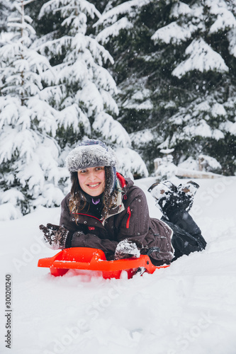 Woman having fun in heavy snow with a sleigh.