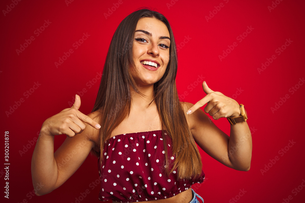 Young beautiful woman wearing casual t-shirt standing over isolated red background looking confident with smile on face, pointing oneself with fingers proud and happy. Young beautiful woman wearing casual t-shirt standing over isolated red background looking confident with smile on face, pointing oneself with fingers proud and happy.