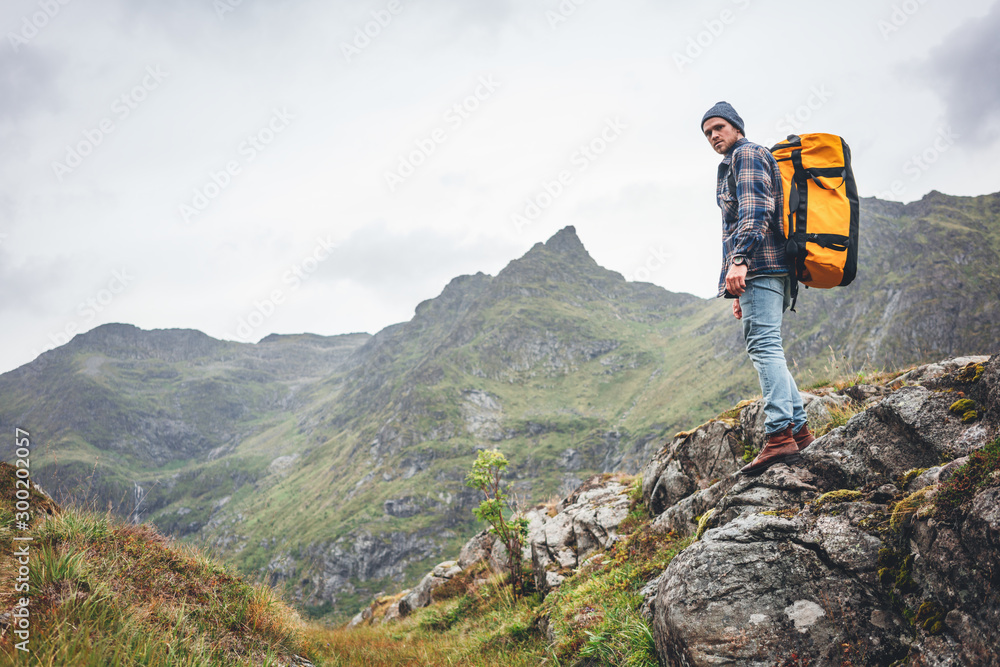 Alone man expeditor wearing professional backpack standing  mountain looking away. Lifestyle adventure vacation