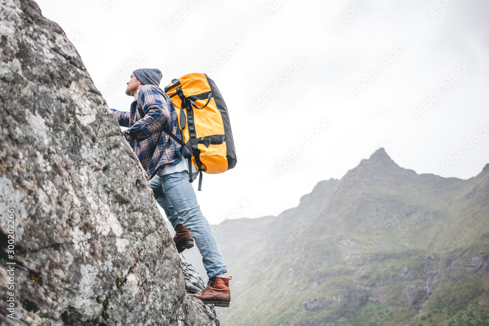 Active man tourist wearing professional backpack to climb on the rock. Brave alone lifestyle tourist conquers the mountain