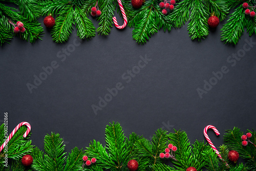 Christmas frame border wirh fir branch, candy cane and baubles on black background