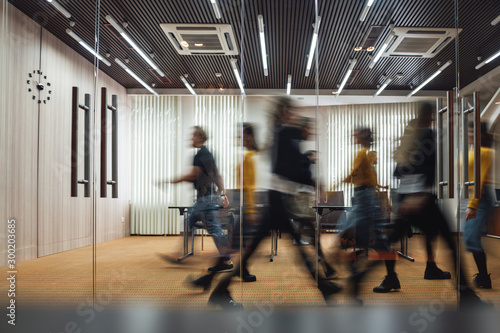 Group of office employees at coworking center. Business people walking at modern open space. Motion blur. Concept photo