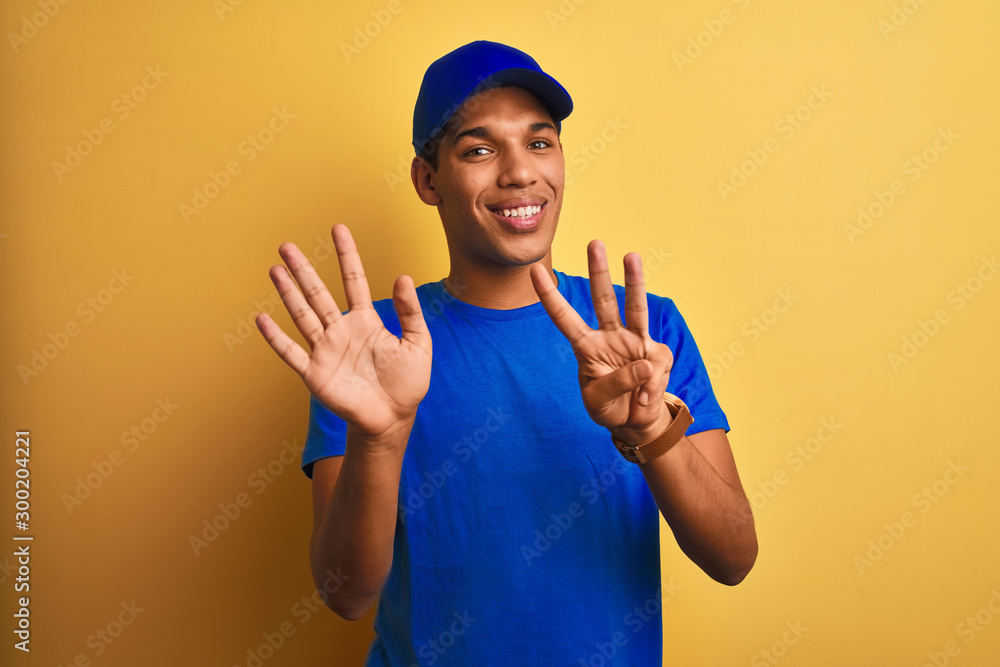 Young handsome arab delivery man standing over isolated yellow background showing and pointing up with fingers number eight while smiling confident and happy.