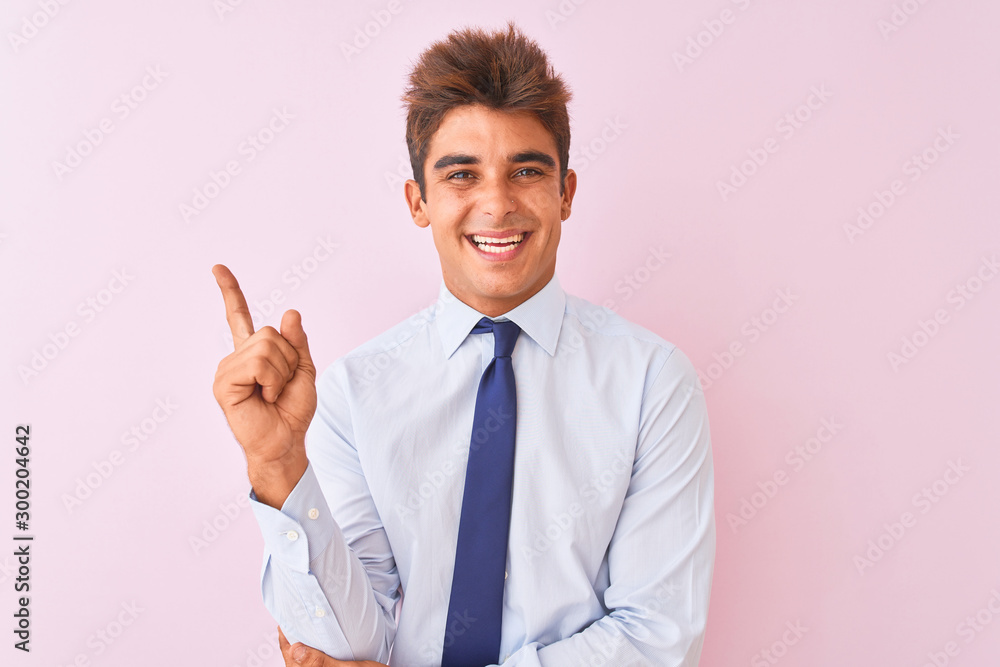 Young handsome businessman wearing shirt and tie standing over isolated pink background with a big smile on face, pointing with hand finger to the side looking at the camera. Young handsome businessman wearing shirt and tie standing over isolated pink background with a big smile on face, pointing with hand finger to the side looking at the camera.