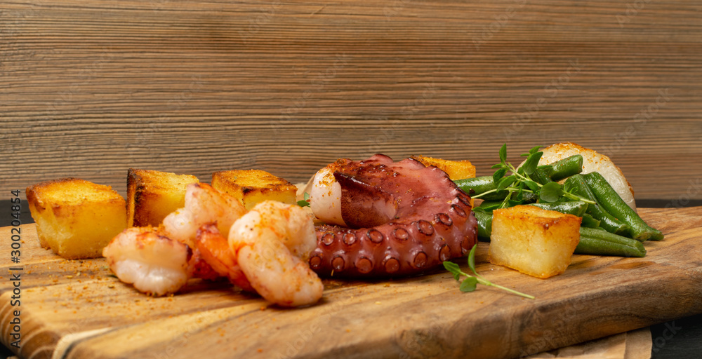 Grilled octopus tentacle on a wooden cut board served with shrimps Grilled octopus tentacle on a wooden cut board served with shrimps