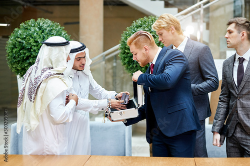 Canvas Print Sheikhs in white suit look at new modern technology in case