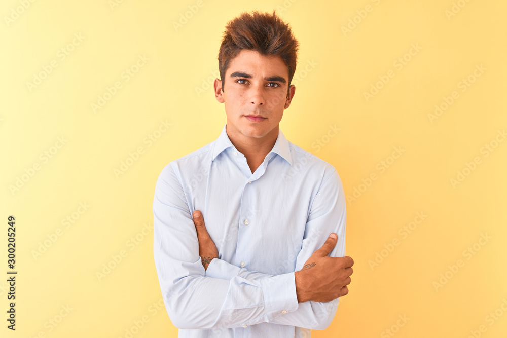 Young handsome businessman wearing elegant shirt over isolated yellow background skeptic and nervous, disapproving expression on face with crossed arms. Negative person. Young handsome businessman wearing elegant shirt over isolated yellow background skeptic and nervous, disapproving expression on face with crossed arms. Negative person.