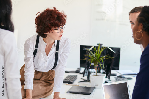 Young caucasian woman wearing eyeglasees look and discuss with business partners working process photo