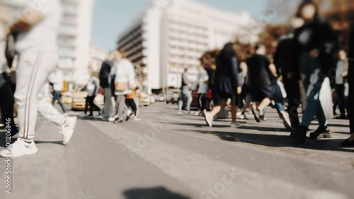 Pedestrians and shoppers commuting in the city on a busy bright day crossing the intersection. No logos trademarks or faces visible.10 bit original BMPCC clip. photo