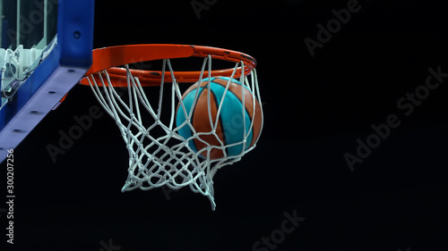 Basketball ring with a net in which the ball flies on a dark background in a sports complex © makedonski2015