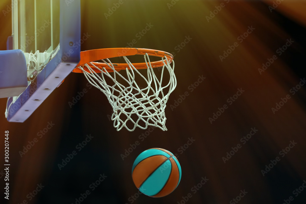 Basketball ring with a net in which the ball flies on a dark background in a sports complex. Toned