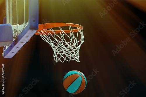 Basketball ring with a net in which the ball flies on a dark background in a sports complex. Toned © makedonski2015