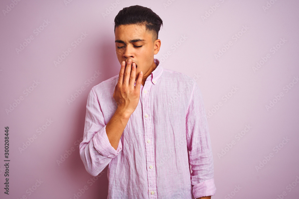 Young brazilian man wearing shirt standing over isolated pink background bored yawning tired covering mouth with hand. Restless and sleepiness. Young brazilian man wearing shirt standing over isolated pink background bored yawning tired covering mouth with hand. Restless and sleepiness.